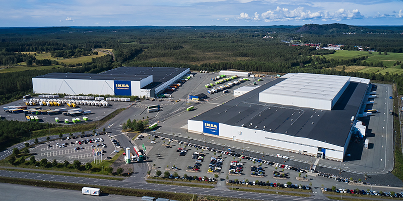 Två av IKEAs byggnader på Torsvik sedda snett uppifrån. I bakgrunden syns skog och himmel.